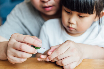 Asian father and daughter are applying nail polish