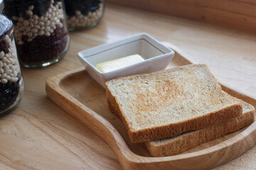 Whole wheat bread in a wooden tray and butter cubes