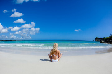 Fototapeta na wymiar Woman back view relaxing on the sandy beach enjoying sunny day on the tropical caribbean island landscape with turquoise sea and blue sky 