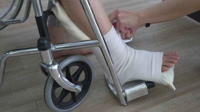 asian doctor exam woman patient who is sitting in the wheelchair and get leg injury from accident. healthcare and medical concept