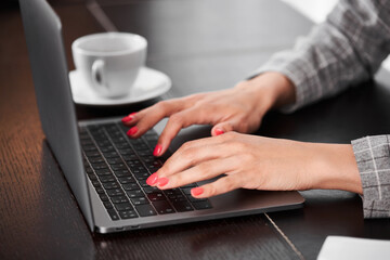  Woman with a laptop. Woman's hands are typing on a laptop. A cup of tea. Using computer concept.