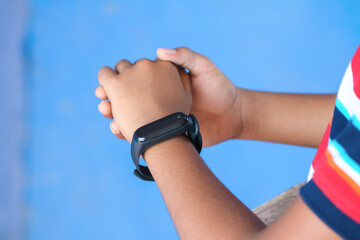 Indian boy wearing smartwatch in his hand	
