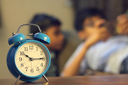 Indian Friends playing video game on smart phone. Alarm-clock is in front of them - Powered by Adobe