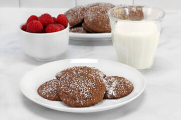 Chocolate cookies, milk and raspberries for an after school snack.