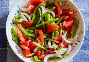 Fresh healthy and delicious vegetable salad with green pepper strips, sliced garden tomato, red onion strips and olive oil.