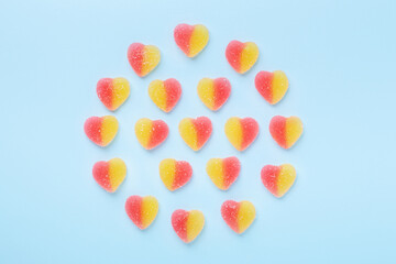 Colorful gummy hearts on blue background. Jelly sweets in circle shaped. Top view