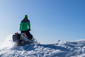 Rider on the snowmobile in the mountains ski resort. A man is riding snowmobile in mountains