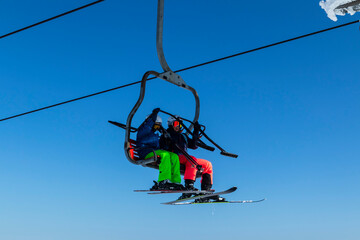 Ski, skiing, skiers on ski lift. Happy people enjoying winter vacations in mountains. Winter...