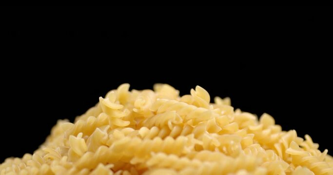 A bunch of dry pasta fusilli rotates slowly.