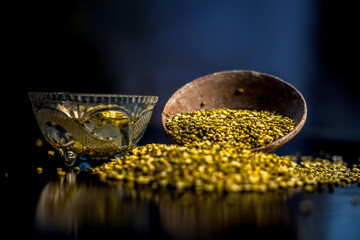 Close shot of mung bean or moong dal in a clay bowl along with some water and moong dal well mixed on a black glossy surface. Horizontal shot with  Rembrandt lighting technique.