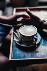 The couple in the cafe holds hands gently. A cup of coffee.