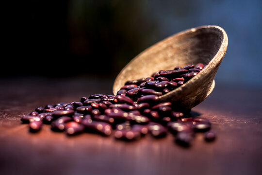Close up of raw kidney beans on brown colored surface in a clay bowl with a spotlight on it. Horizontal shot.