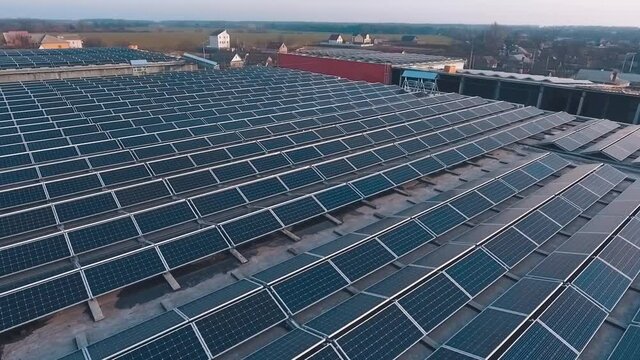 Innovative solar farm at sunset. Photovoltaic panels in rows on the roof of buildings in the countryside. Renewable energy.
