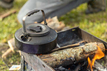 Teapot warming up on a camping fireplace.