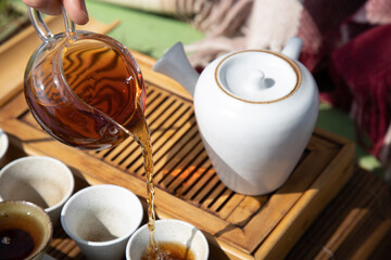 Tea ceremony at the outdoors camping site. Pouring some tea