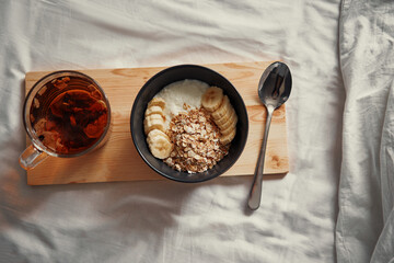 Good morning. Breakfast in bed. Bowl of granola and cup of hot tea.