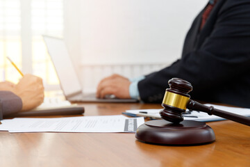 Wooden gavel on table in lawyer's office. Lawyer having team meeting with the client. Concepts of law, advice, legal services.