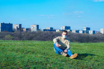 medical mask as protection against coronavirus. guy sits in a clearing away from the city hiding from the coronavirus