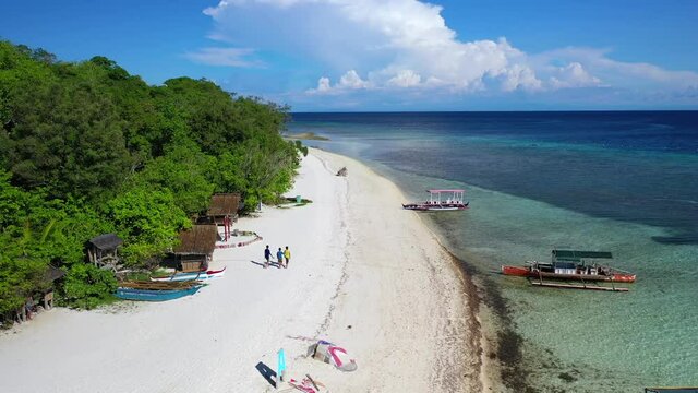 Banca boats near Mantigue Island tropical beach in the Philippines, backwards aerial