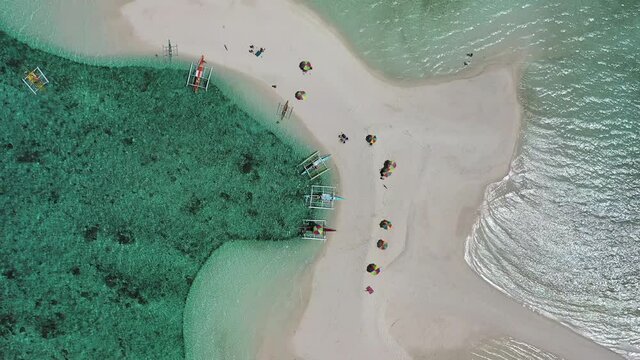 Banca boats and beach umbrellas on White Island sandbar near Camiguin, overhead aerial