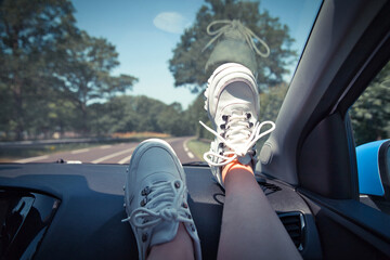 Freedom car travel concept - woman relaxing with feet on dashboard wearing white sneakers. Sexy woman in the car.