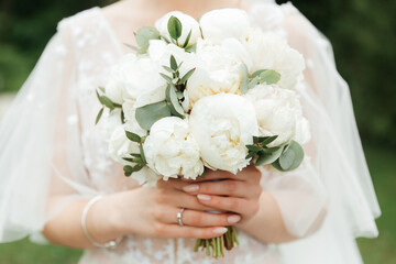 luxurious bouquet in the hands of the bride in a wedding dress and veil, rings
	
