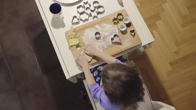 Top view of a little girl making biscuits at the kitchen table