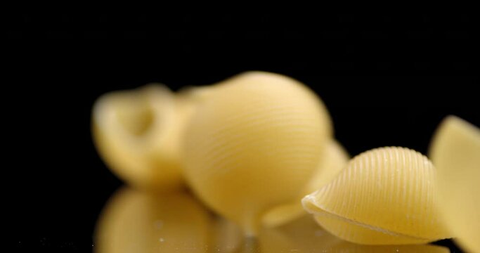 Dry pasta rigati falls on the table.