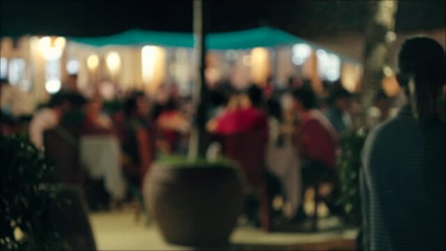 Blurred defocused image of night festival in street restaurant, background with color bokeh.