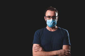 Adult person with protective face mask posing on a black background - social issues with virus and...