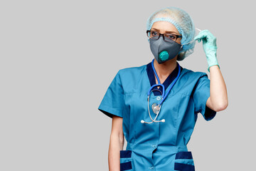 female doctor with stethoscope wearing protective mask and latex gloves over light grey background