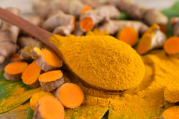 Turmeric powder,leaves and fresh turmeric (curcumin) on wooden background,Used for cooking .