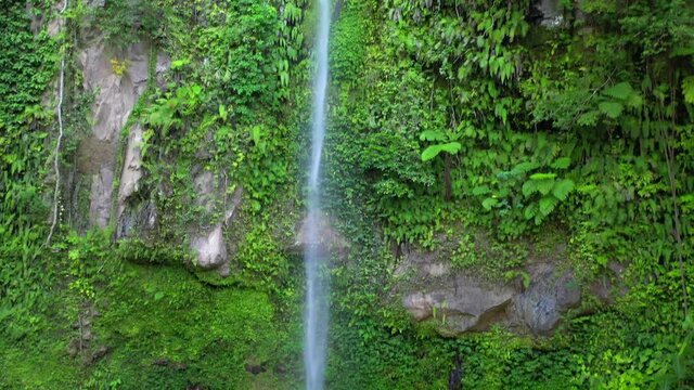 Katibawasan Falls tall waterfall in lush rainforest, rising pedestal aerial