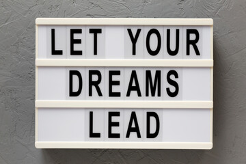 'Let your dreams lead' on a lightbox on a gray background, top view. Flat lay, from above, overhead.
