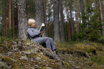 Naklejka na ściany i meble girl reading a book in the forest