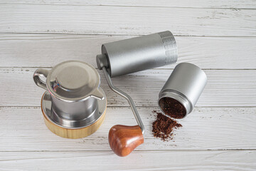 Barista making drip coffee, coffee beans are in an antique hand-cranked coffee bean grinder on old wooden background.