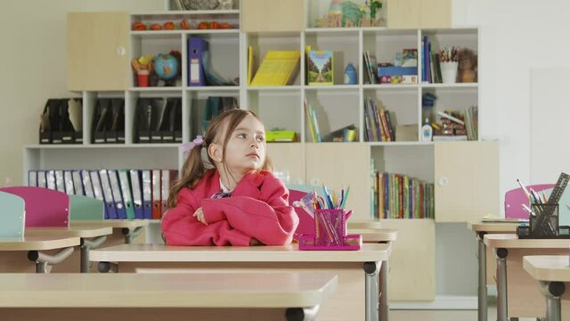 A child at school who sits at a desk, misses and goes to bed. A child who is bored at school at the desk while studying.