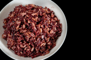 Thai riceberry mixed Thai jasmine rice in bowl on a black background.