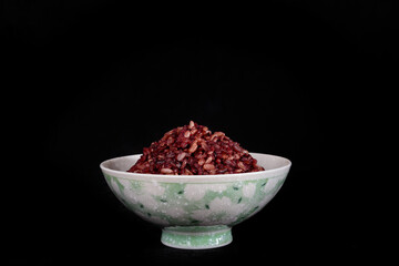 Thai riceberry mixed Thai jasmine rice in bowl on a black background.