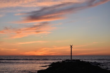 Coucher de soleil sur la côte Atlantique française, à Soulac-sur-Mer. Une digue rocheuse avance dans l'océan. Ce paysage est très coloré, il est calme et reposant.. La lumière est belle est douce.