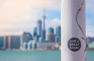 Live a great story motivational sticker on a pole with Toronto city skyline in background