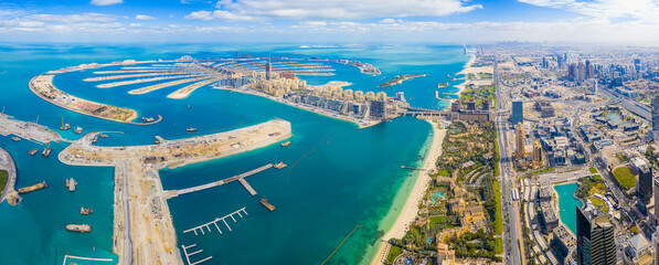 Panoramic aerial view of Palm Jumeirah Islands in Dubai; Man-made palm tree shaped islands in dubai on cloudy blue day