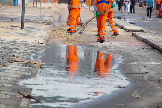 cleaning workers removing sand from the Leblon beach boardwalk in Rio de Janeiro