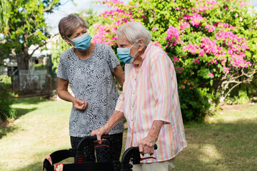 Two older ladies wearing masks in garden
