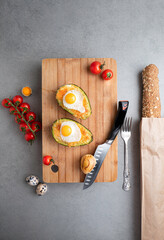 Baked avocado with eggs and cheese on a wood cutting board.