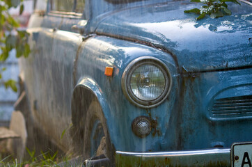 Fototapeta premium blue car with round headlights in the summer rain