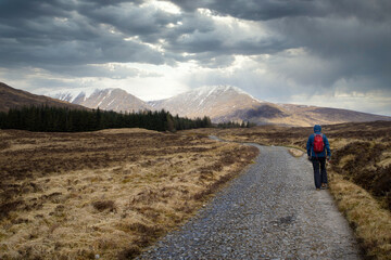 Bridge of Orchy (Scotland), April 2019. Hiker walking towards the sun on the West Highland Way.