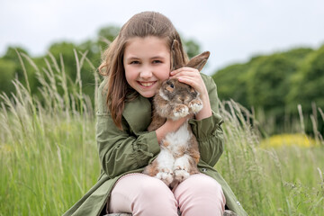Cute red haired domestic rabbit. The girl holds a fluffy animal in her arms. Pet care concept