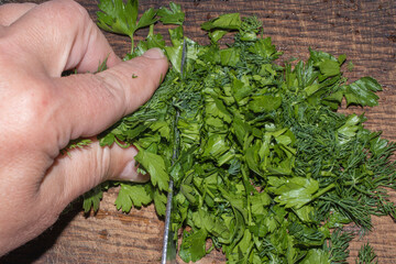 Slicing parsley and dill on a wooden board