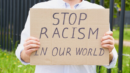 Stop racism concept. Unrecognizable white person holds sign with text against racist.